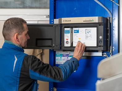 DeLaval technician operating a Milk Cell Analysis control unit in a dairy facility.
