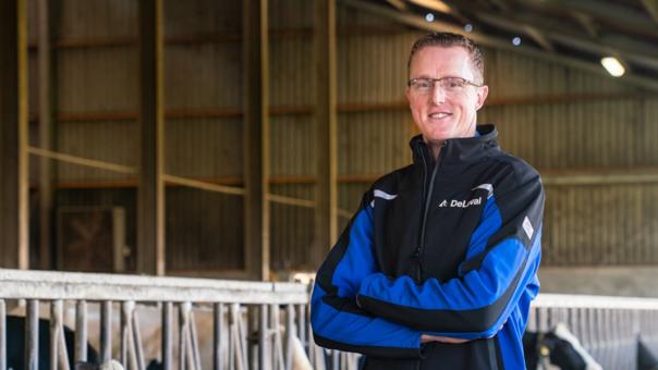 Martin stands in his barn with cows in the background