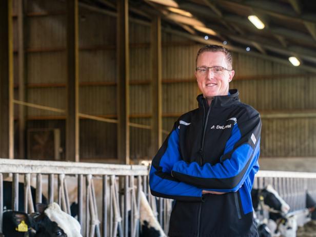 Martin stands in his barn with cows in the background