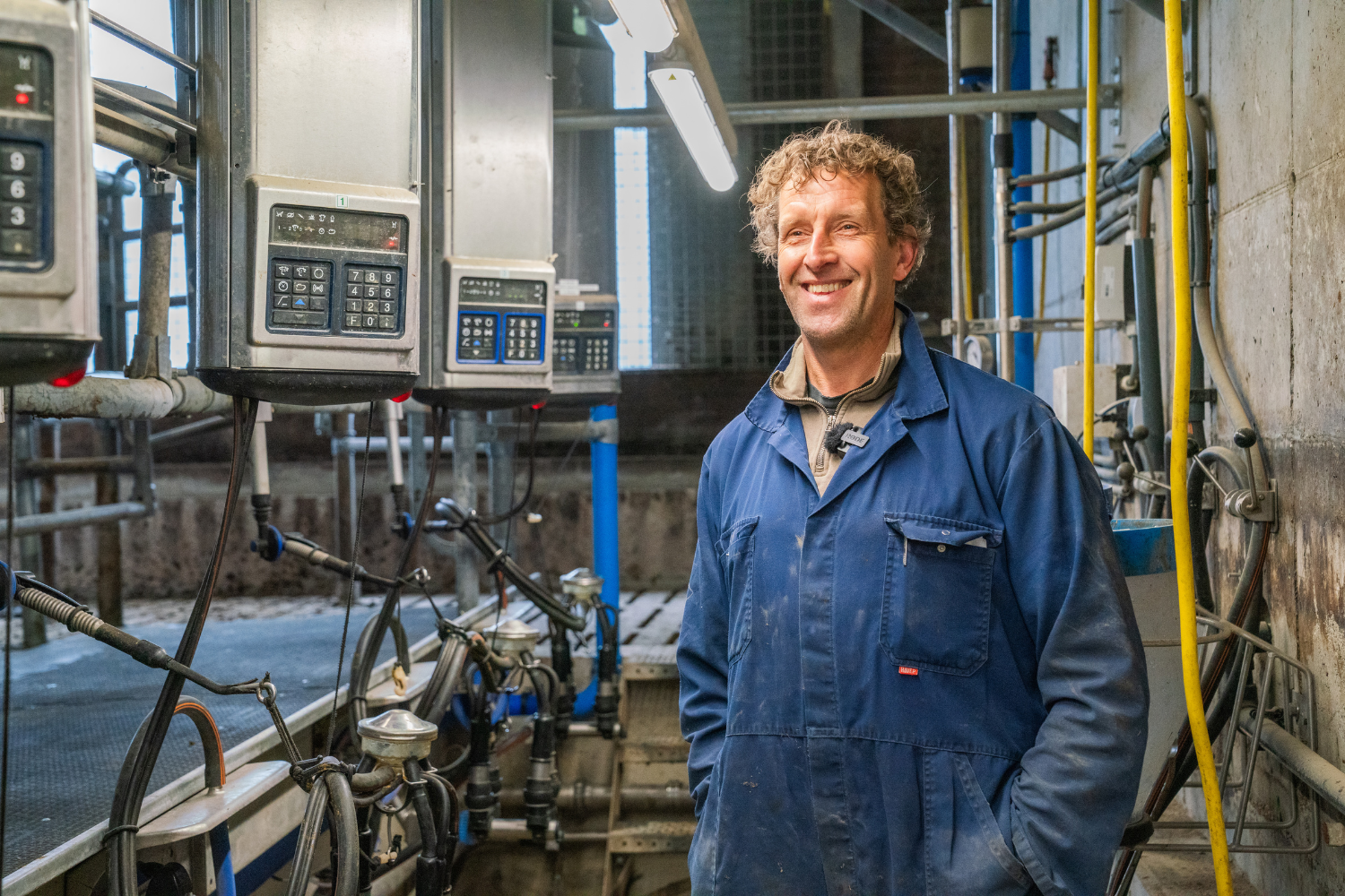 Medewerker Offenberg Nanne Zuidema met de 1x5 melkstal naast de VMS Batch Milking systeem