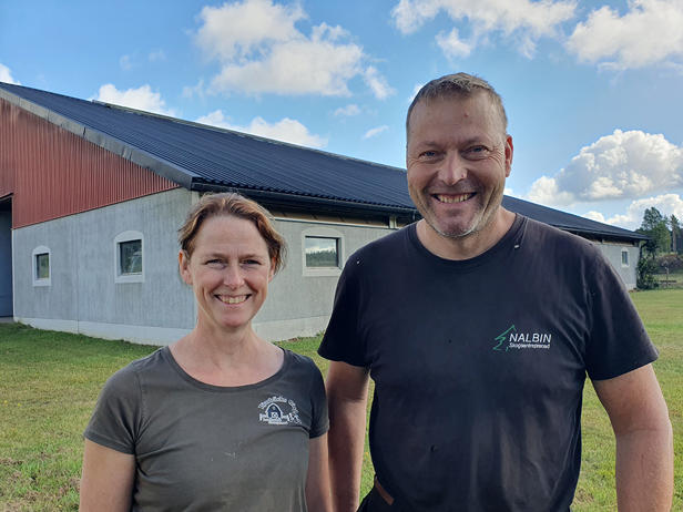Lantbrukarna Karin och Sven Nalbin står i kortärmat framför stallbyggnaden en sommardag